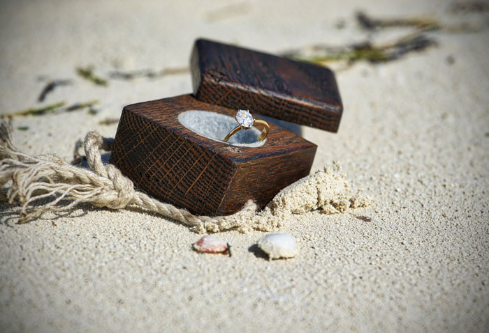 engagement ring in a box on the beach