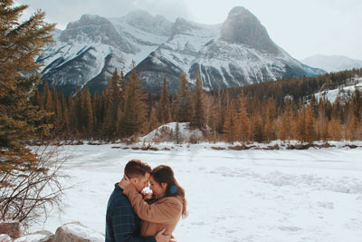 couple hugging in front of wintery mountain scape